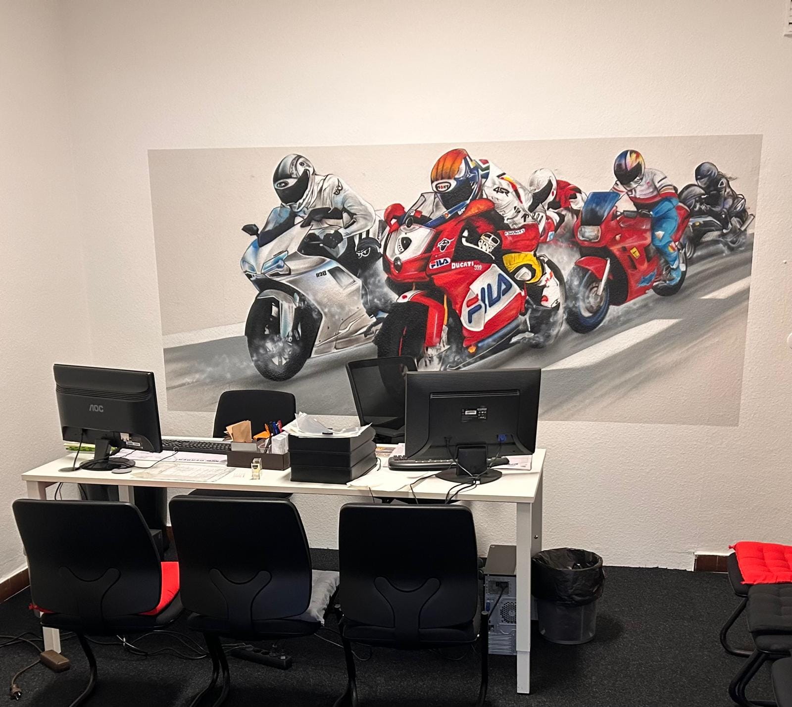 Büro der Fahrschule Zanke mit einem großformatigen Motorradrenn-Motiv an der Wand.